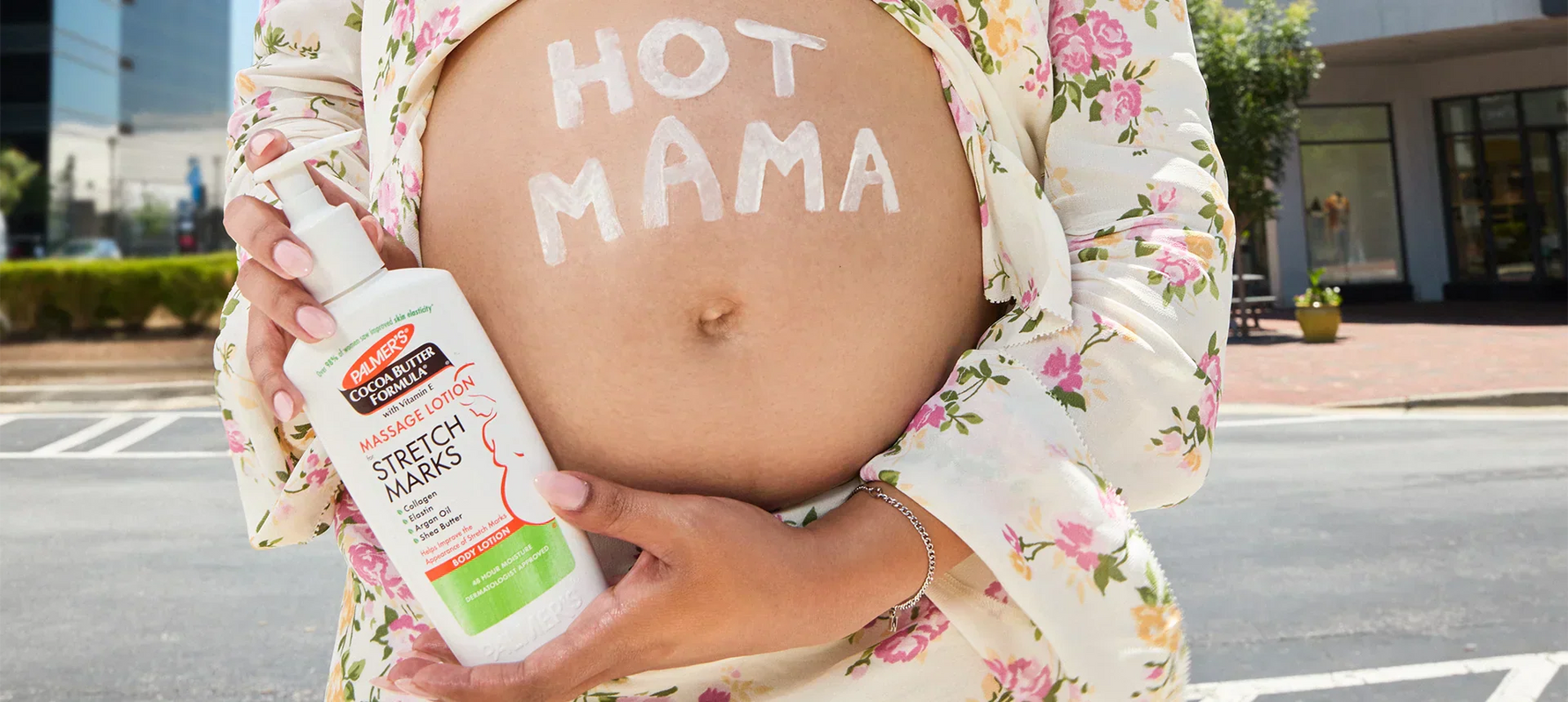 Pregnant woman with Hot Mama written on belly holding bottle of Palmer's Massage Lotion for Stretch Marks